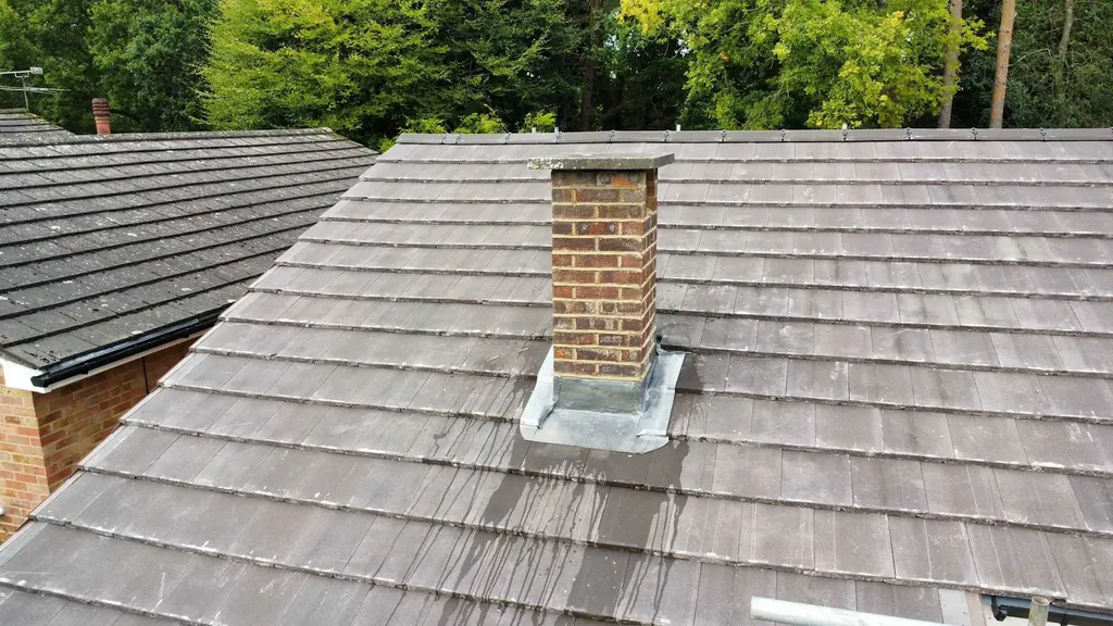 Brick chimney with lead flashing on a grey tiled roof