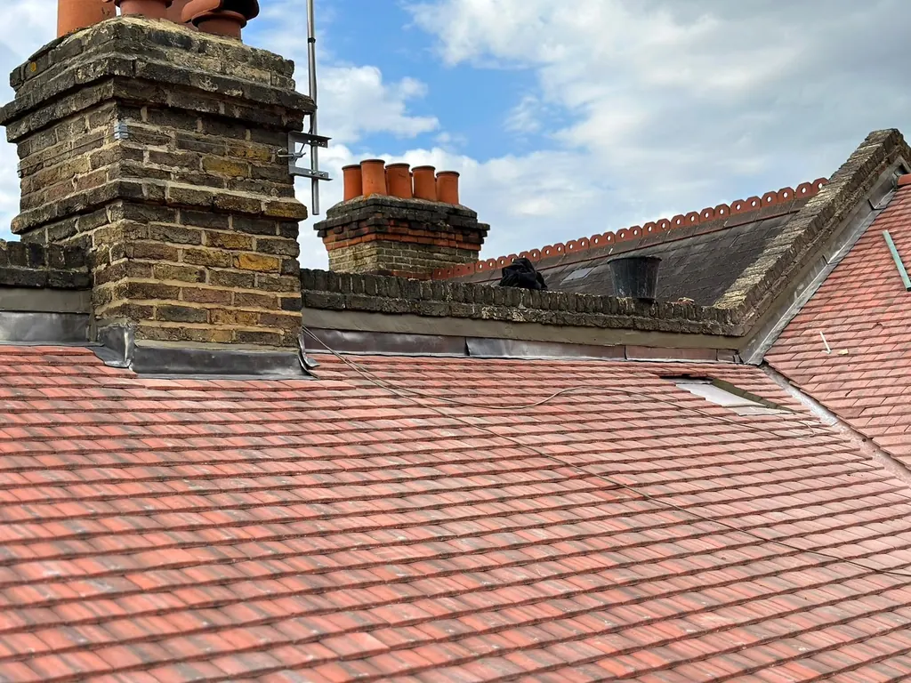 Brick chimneys and lead flashing on red tiled roof planes