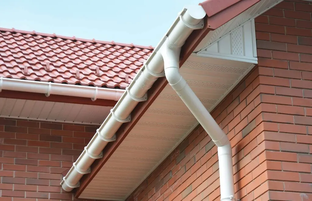 White gutter and downpipe around a brick house corner