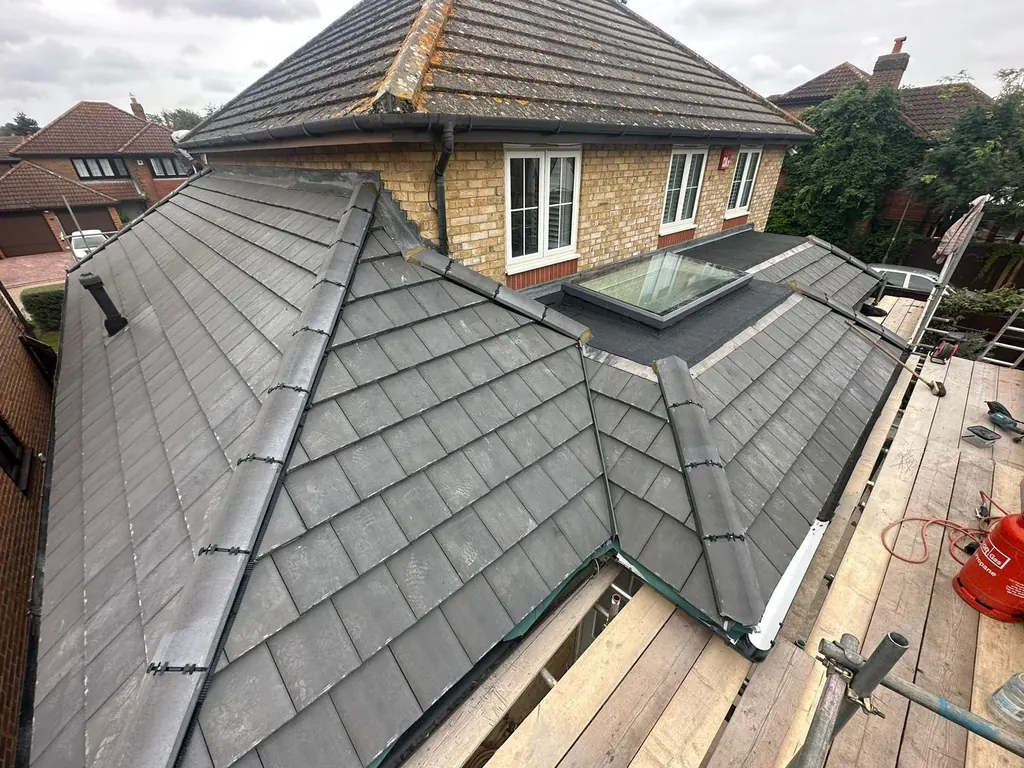 Intersecting grey tiled roof planes beside a scaffold walkway