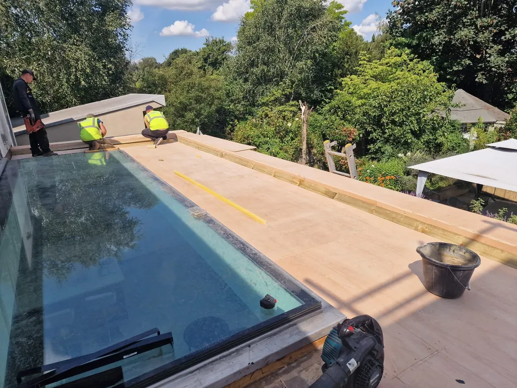Roofers beside a large glazed rooflight on a timber deck