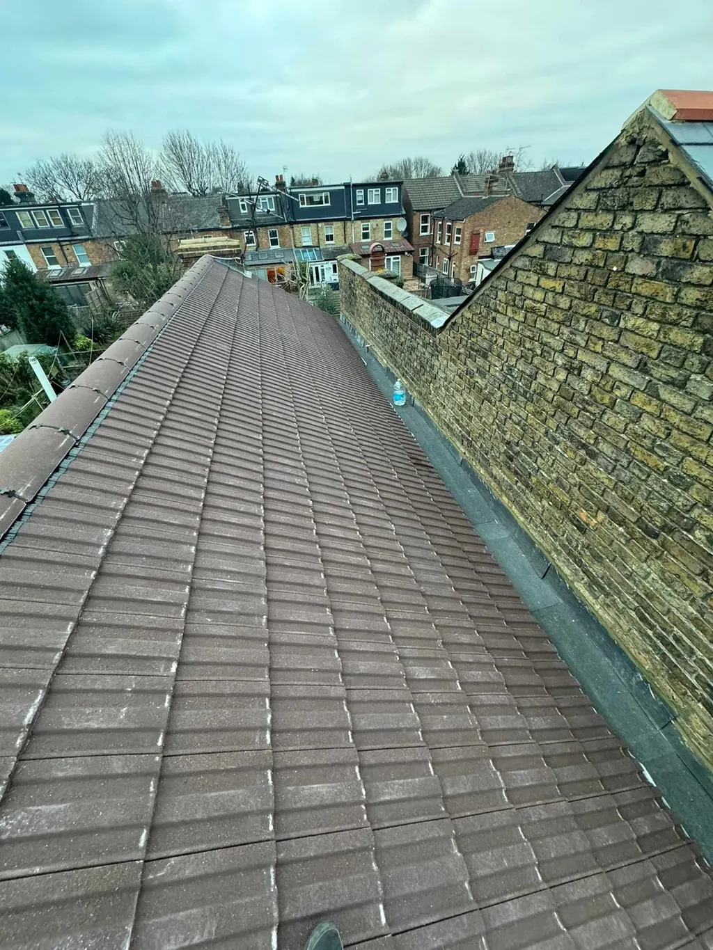 Long grey tiled roof beside a stone gable
