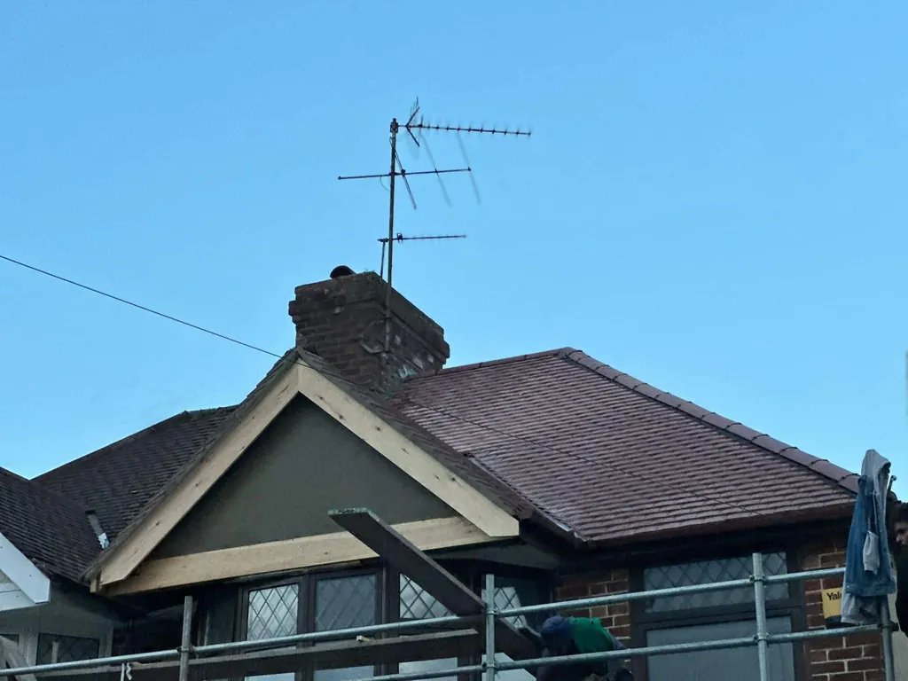 Red tiled gable roof and chimney under clear blue sky