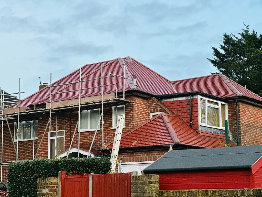 Red hipped tiled roof on a brick house with scaffold